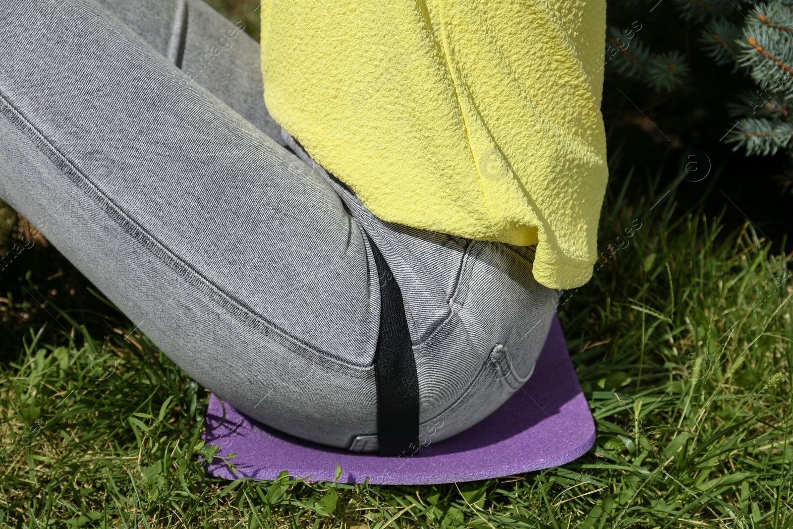 Photo of Woman sitting on foam tourist mat outdoors, closeup