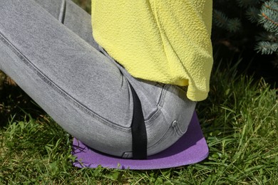 Photo of Woman sitting on foam tourist mat outdoors, closeup