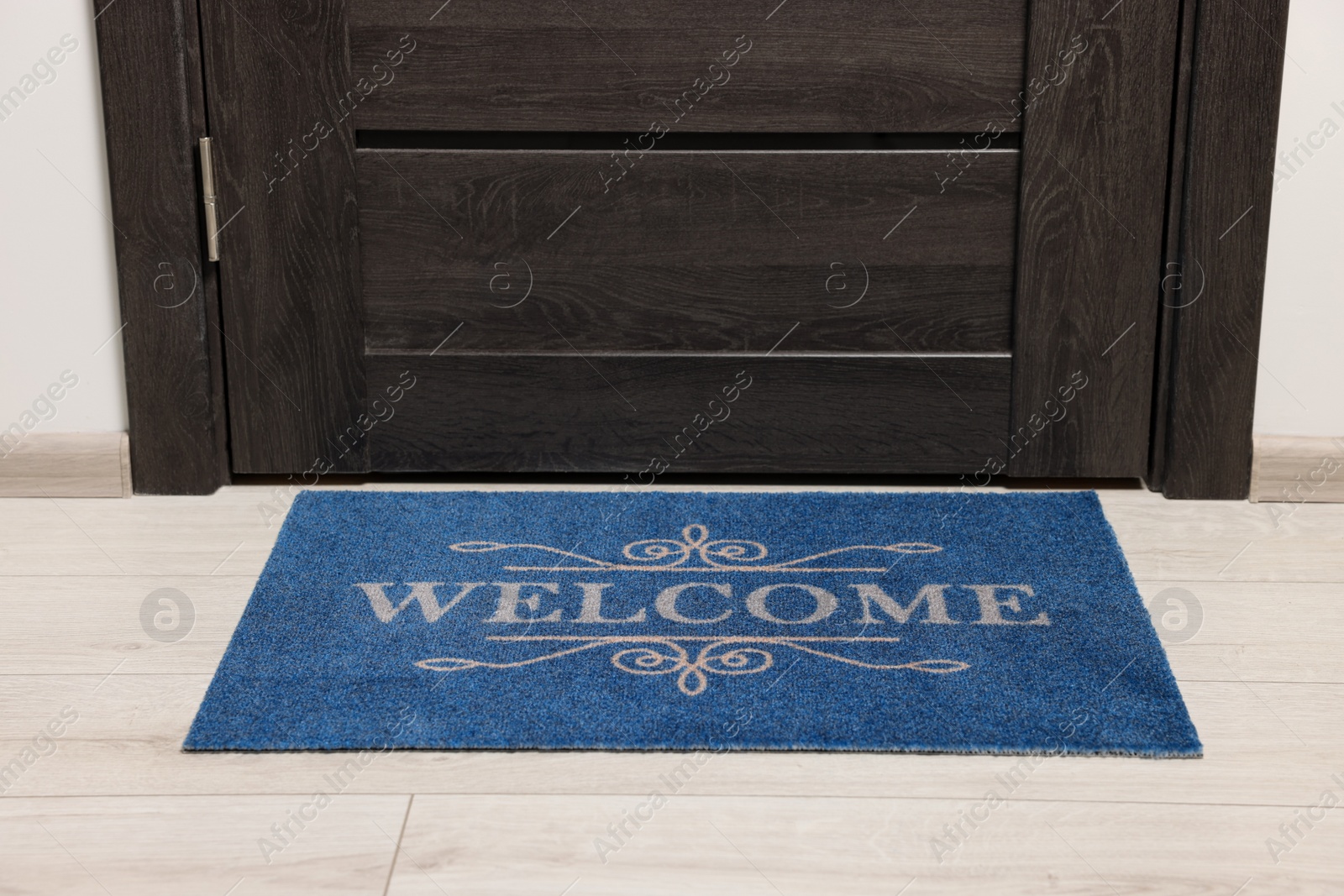 Photo of Blue doormat with word Welcome on white floor near entrance