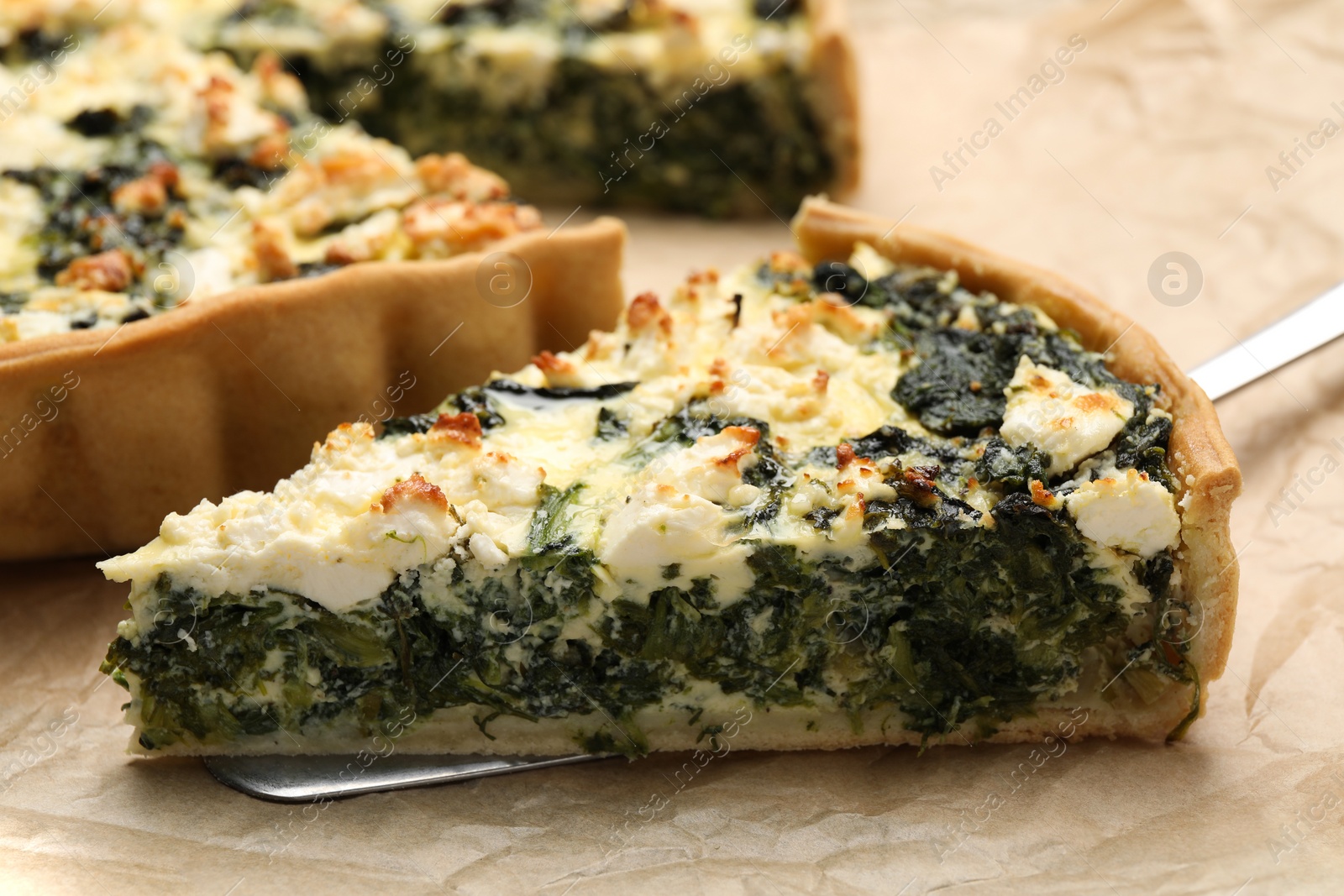 Photo of Delicious homemade spinach quiche on parchment paper, closeup