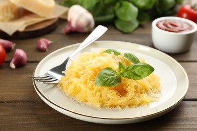 Photo of Tasty spaghetti squash with basil and cheese served on wooden table