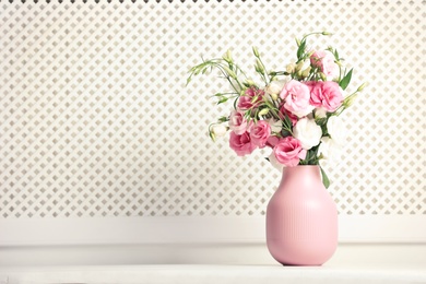 Photo of Vase with beautiful flowers on table against white wall, space for text