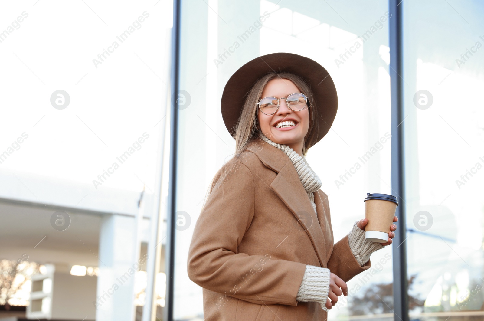 Photo of Young woman with cup of coffee on city street in morning