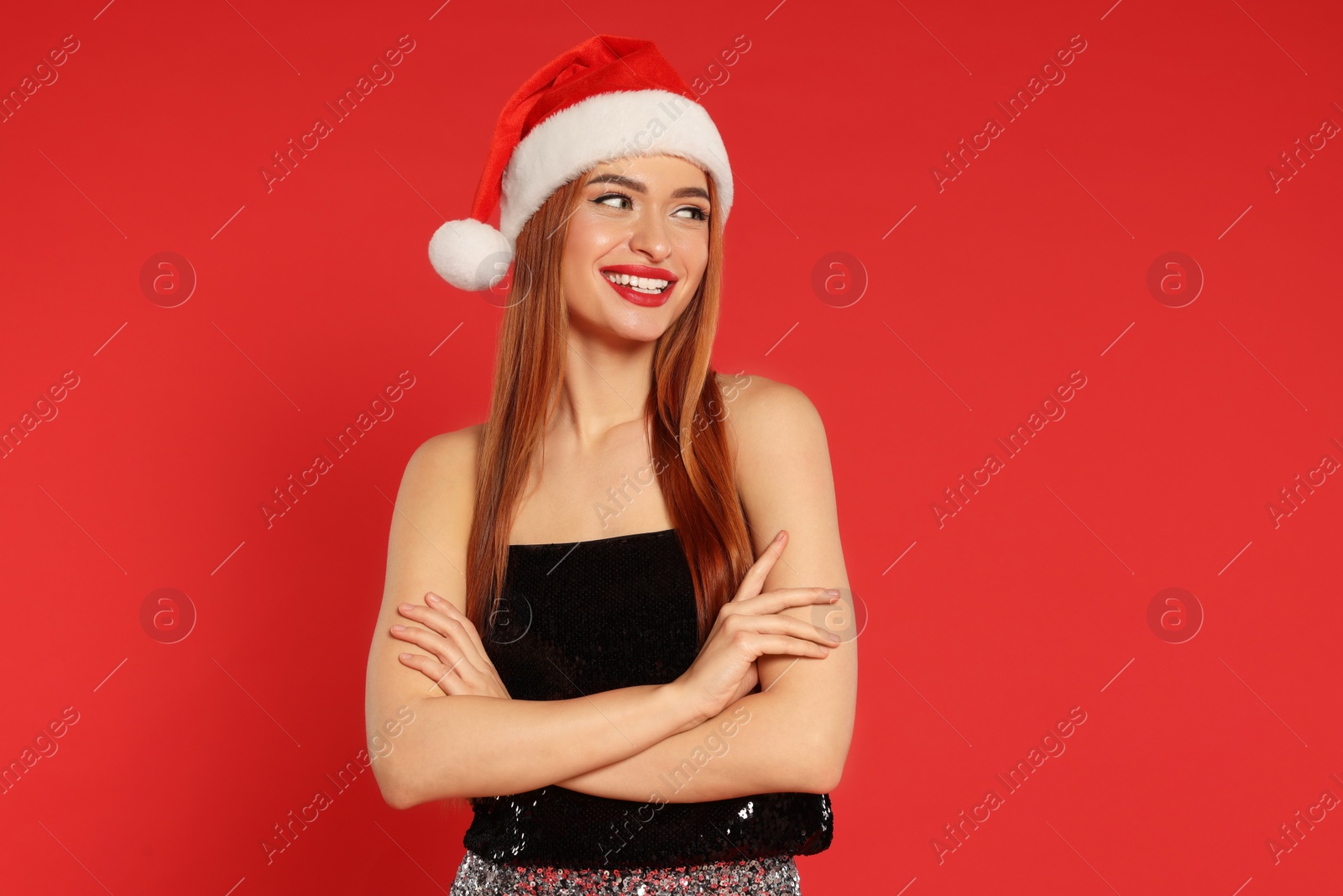 Photo of Young woman in Santa hat on red background. Christmas celebration