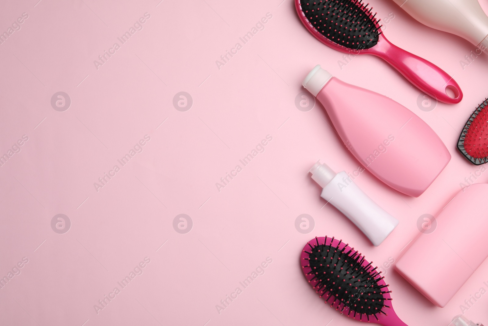 Photo of Flat lay composition with hair cosmetic products and tools on pink background. Space for text