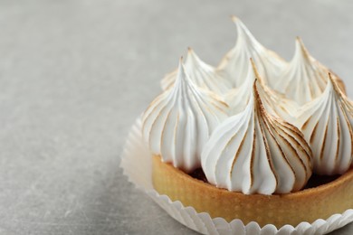 Delicious dessert. Tartlet with meringue on light grey table, closeup. Space for text