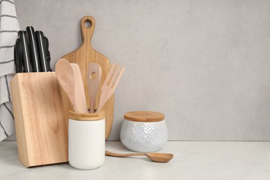 Photo of Set of different kitchen utensils on white near gray wall. Space for text