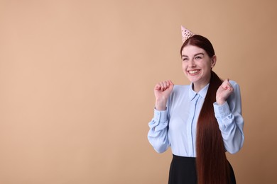 Photo of Happy woman in party hat on beige background, space for text