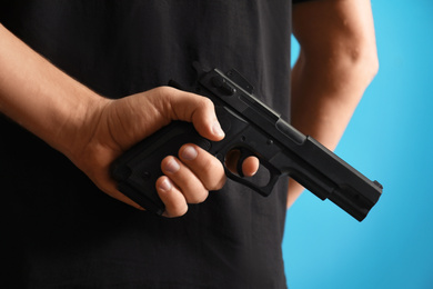 Photo of Man holding gun on blue background, closeup