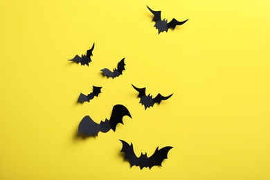 Photo of Paper bats on yellow background, flat lay. Halloween decor