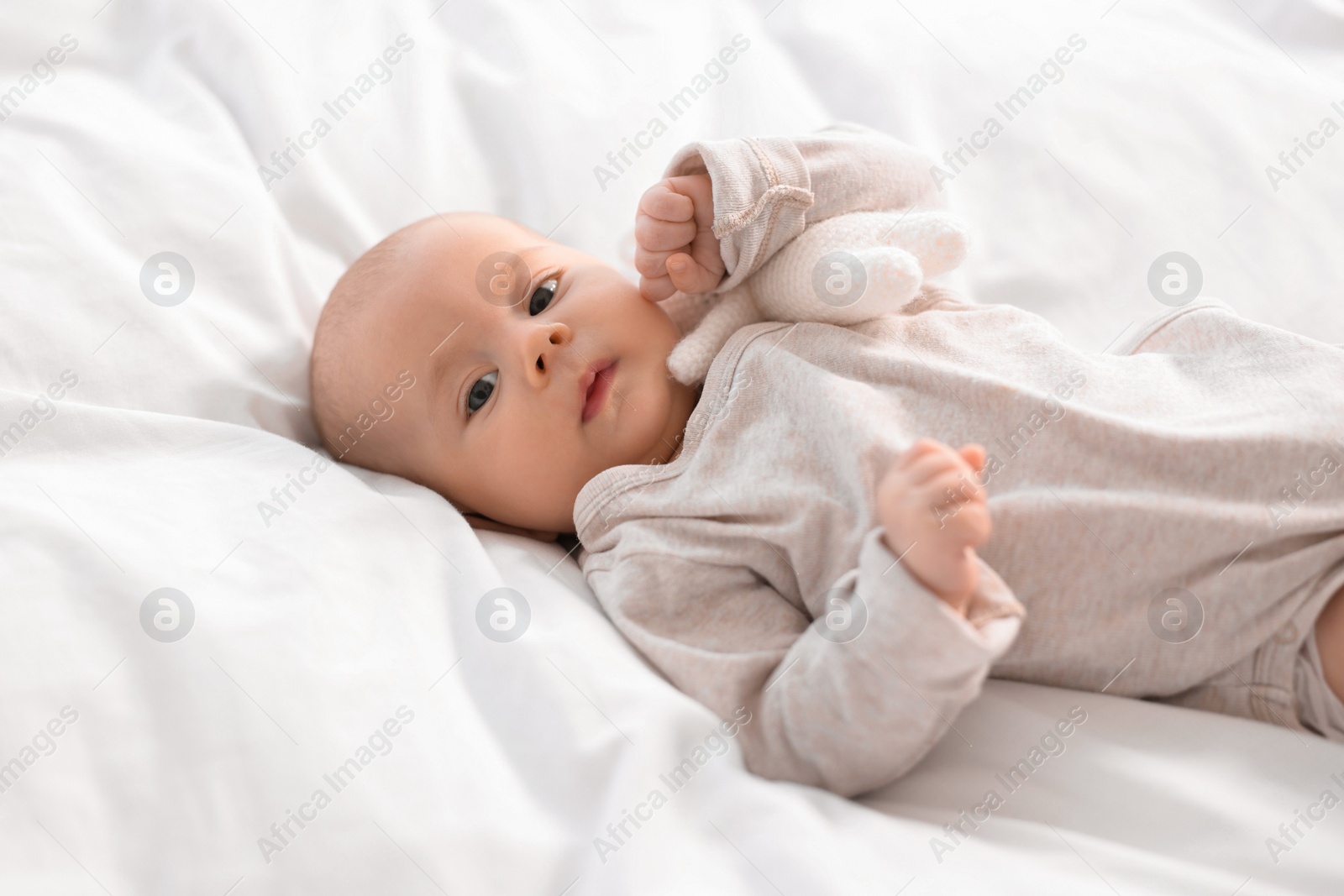 Photo of Cute little baby lying on white sheets