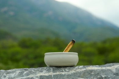 Photo of Burnt palo santo stick on stone surface in high mountains