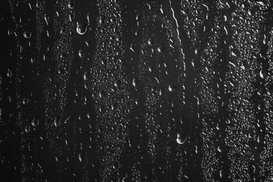 Photo of Glass with rain drops against dark background