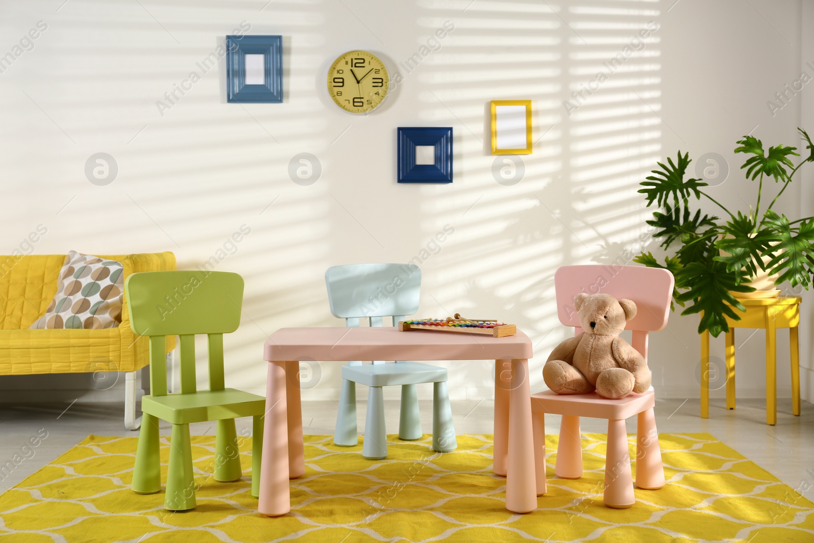 Photo of Stylish playroom interior with table, chairs and sofa