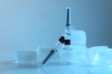 Photo of Syringes with COVID-19 vaccine and ice cubes on white table