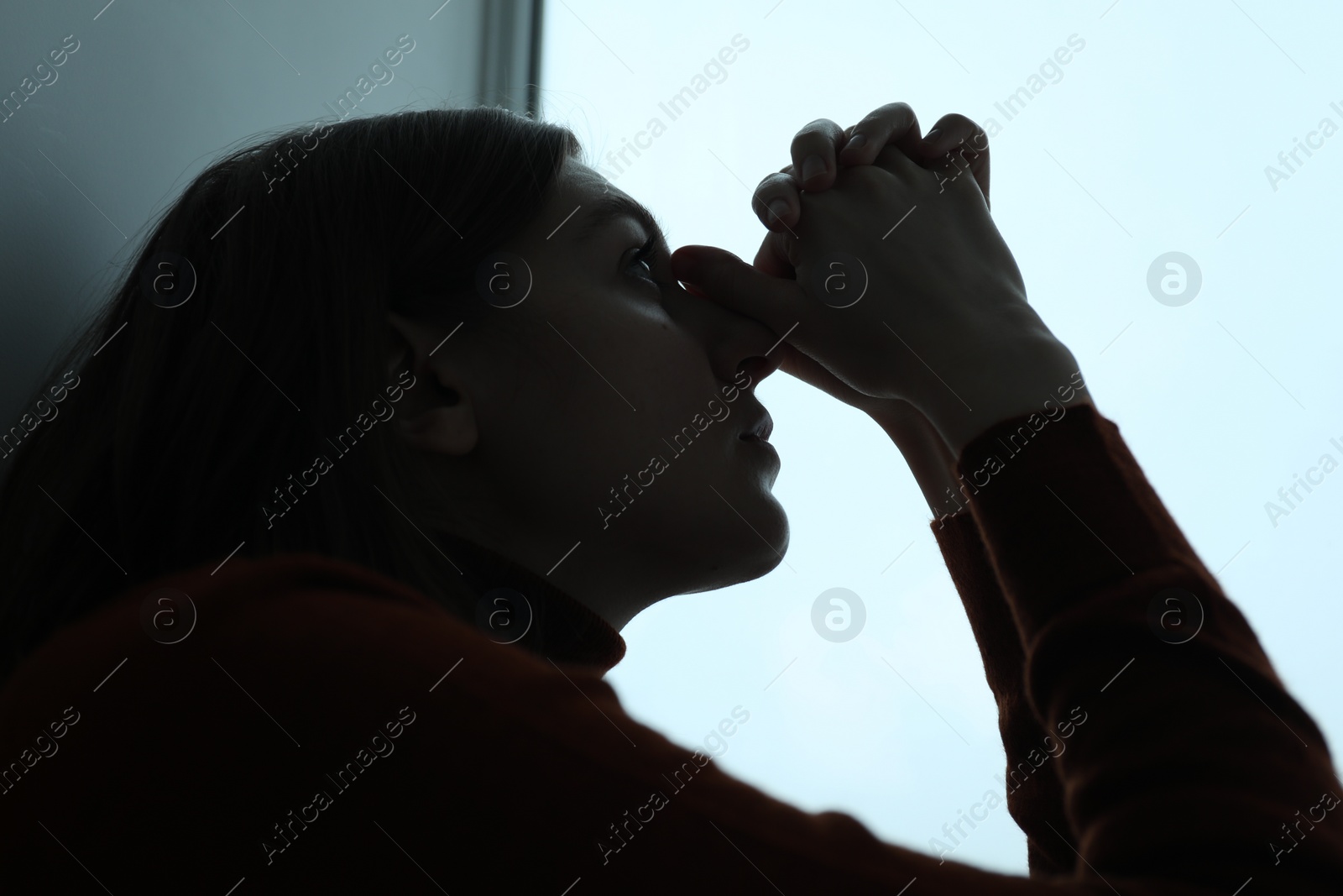 Photo of Sad young woman near window at home, closeup