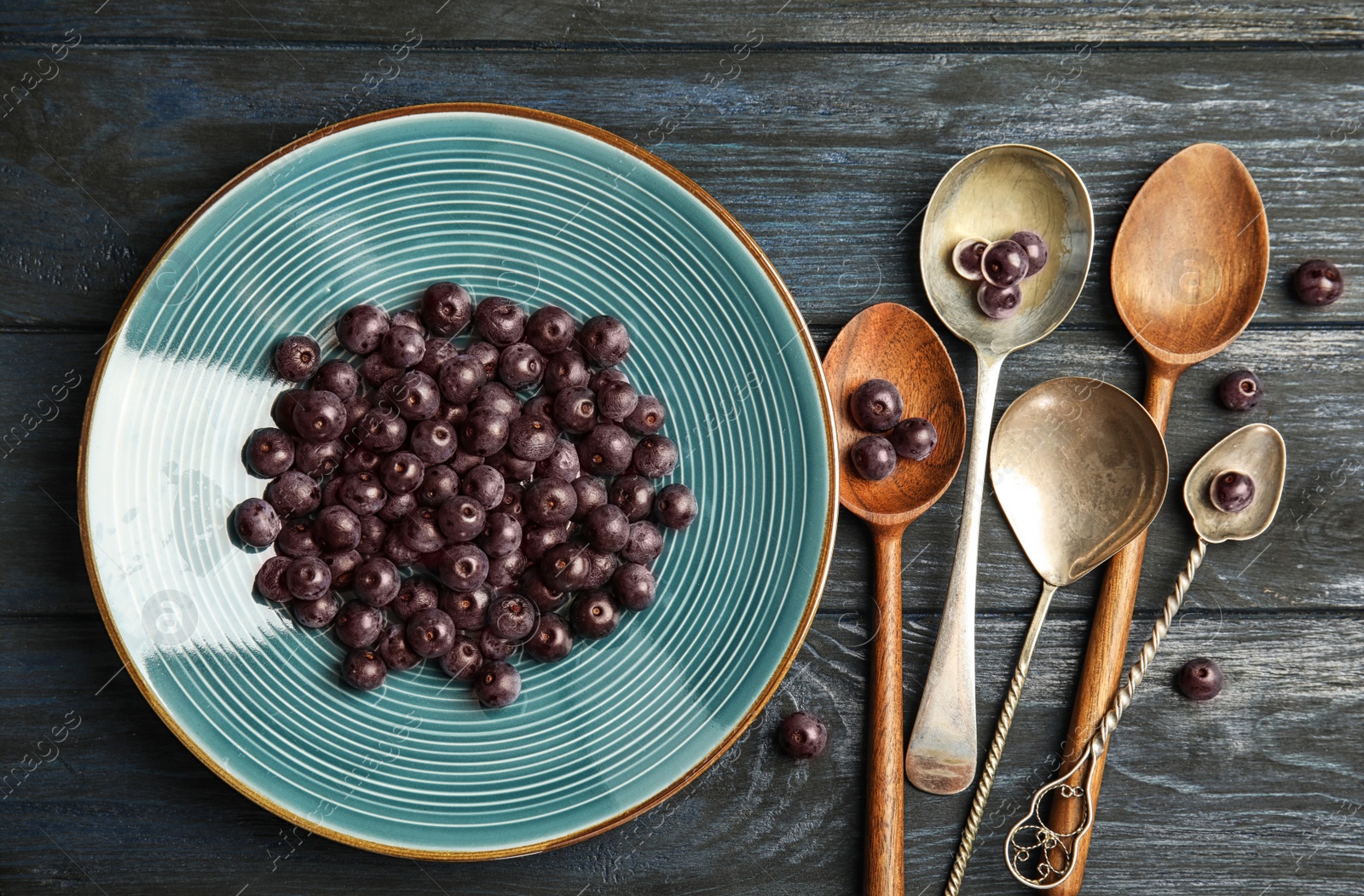 Photo of Plate with fresh acai berries and spoons on wooden table, top view