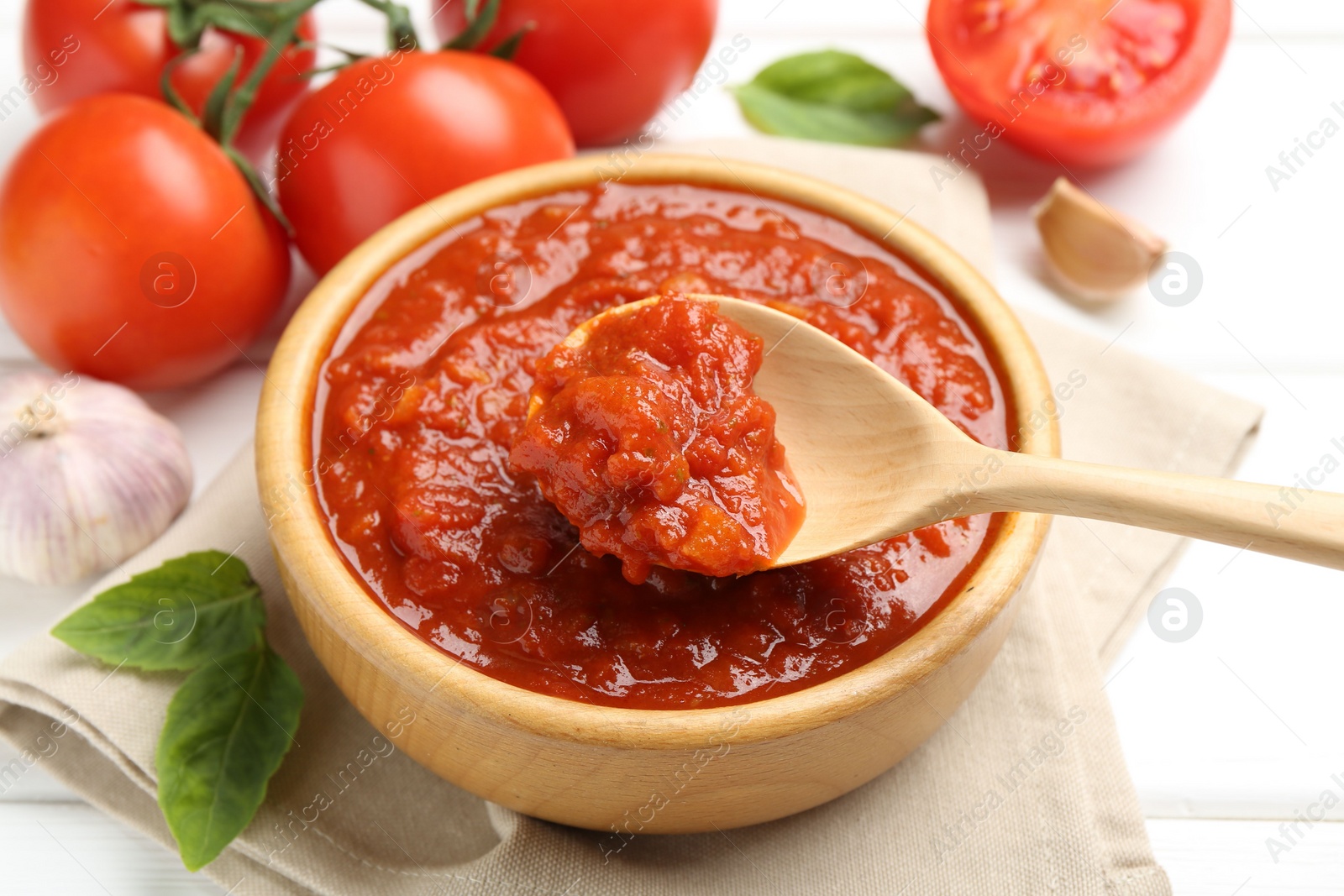 Homemade tomato sauce and spoon in bowl on white table, closeup Photo of Homemade tomato sauce and spoon in bowl on white table, closeup