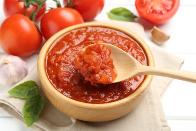 Photo of Homemade tomato sauce and spoon in bowl on white table, closeup