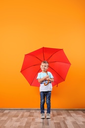 Photo of Little boy with red umbrella near color wall