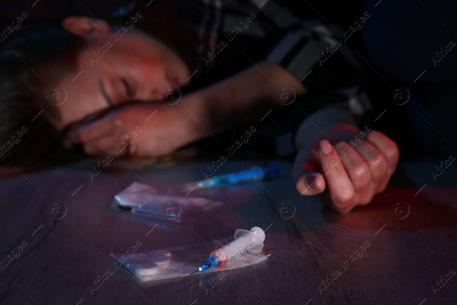 Photo of Addicted woman lying indoors, focus on different drugs