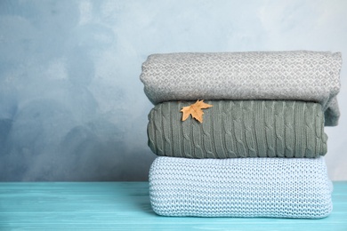 Stack of soft plaids and dry leaf on light blue wooden table. Space for text