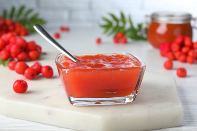 Photo of Delicious rowan jam in glass bowl on white wooden table