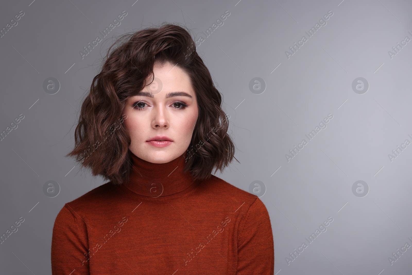 Photo of Portrait of beautiful young woman with wavy hairstyle on grey background. Space for text