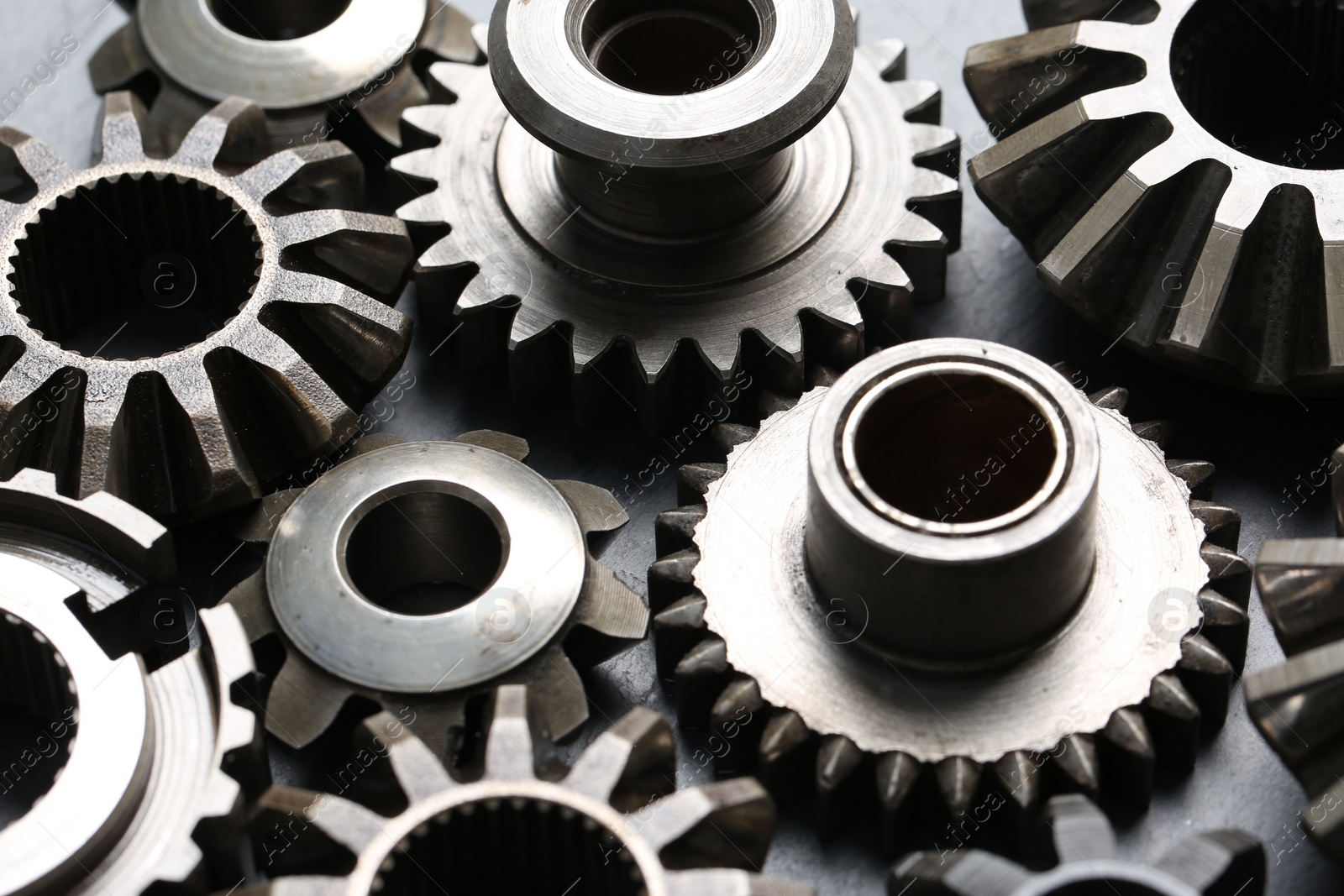 Photo of Many different stainless steel gears on grey background, closeup