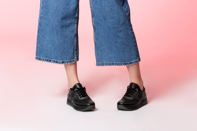 Woman in stylish shoes on color background, closeup