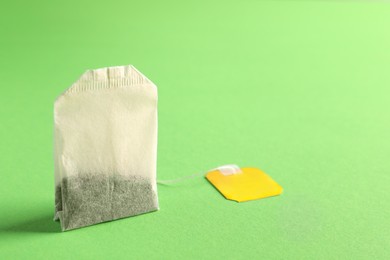 Photo of New tea bag with tab on green background, closeup. Space for text
