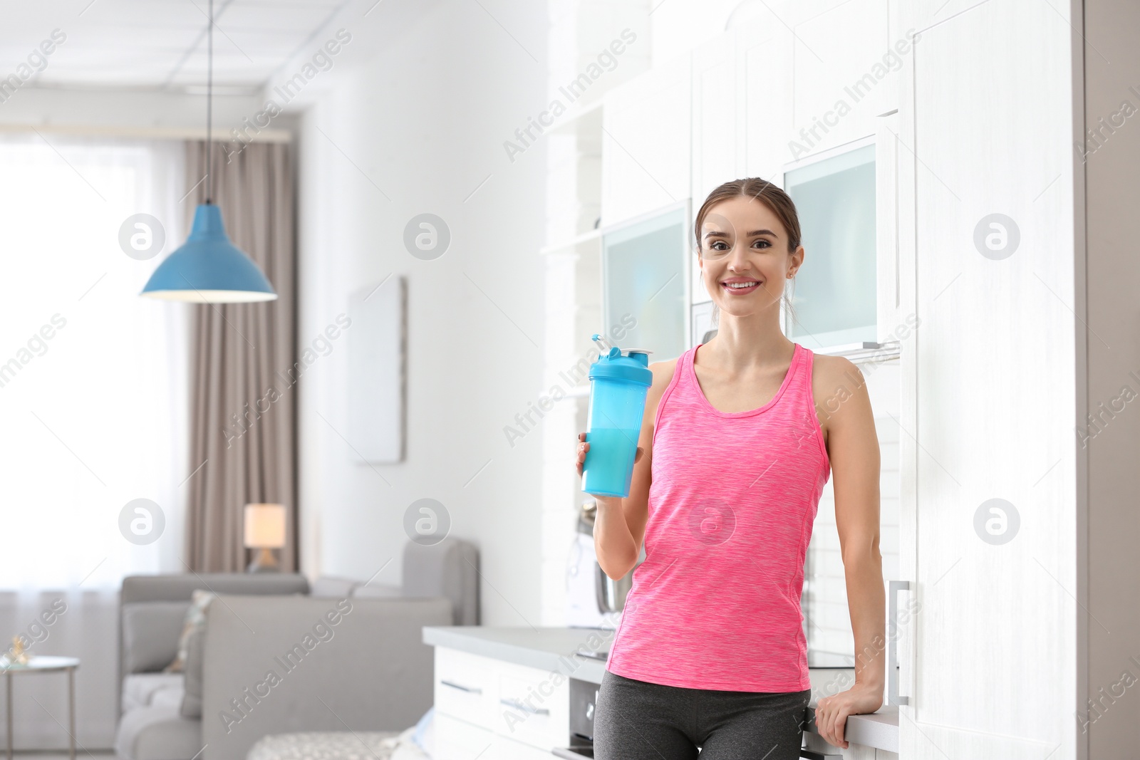 Photo of Athletic young woman with protein shake in kitchen