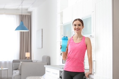 Athletic young woman with protein shake in kitchen