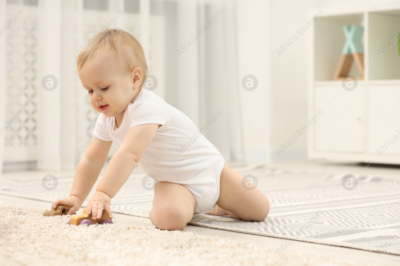 Photo of Children toys. Cute little boy playing with wooden cars on rug at home