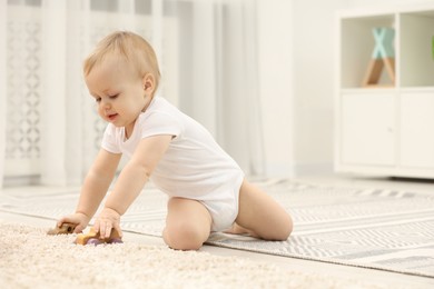 Children toys. Cute little boy playing with wooden cars on rug at home