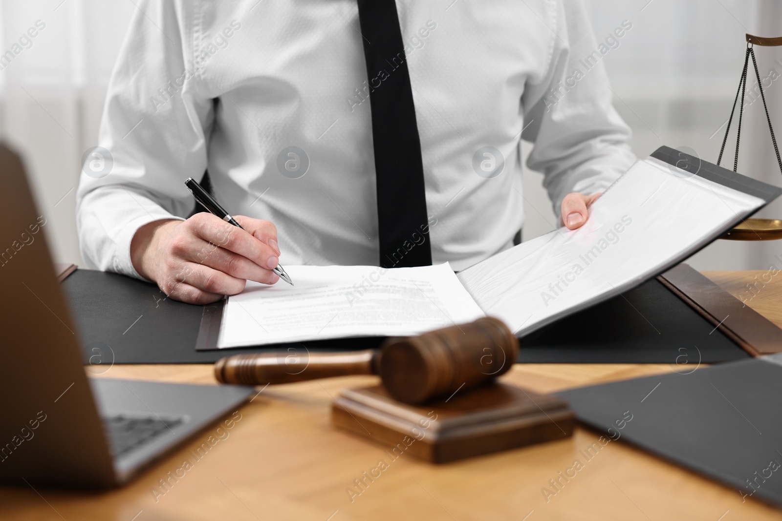 Photo of Lawyer working with documents at wooden table indoors, closeup