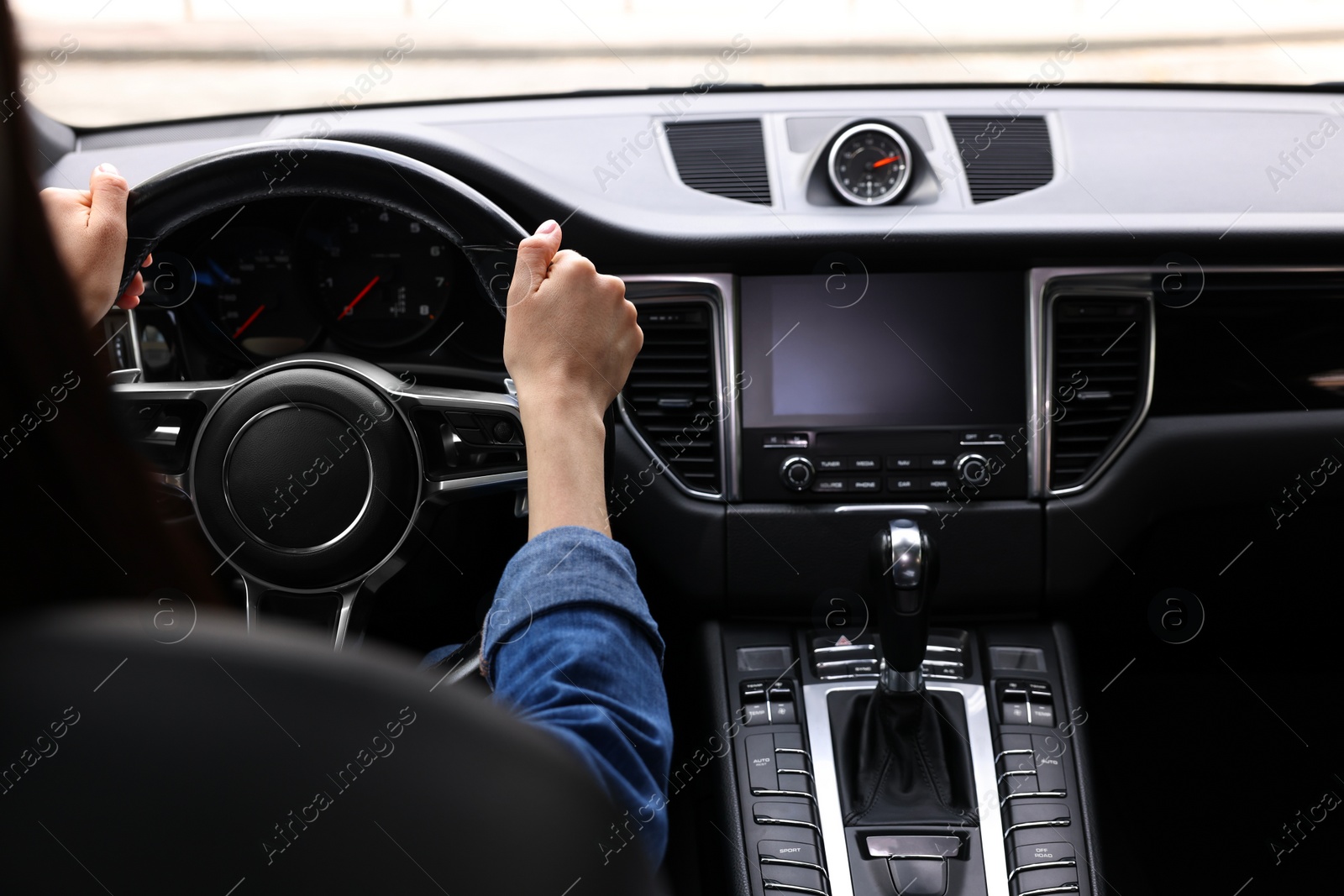 Photo of Woman holding steering wheel while driving her car, closeup