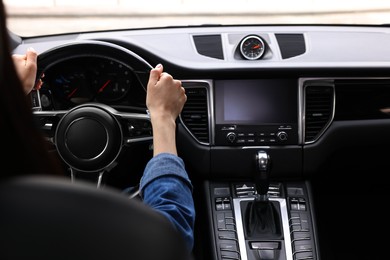 Photo of Woman holding steering wheel while driving her car, closeup