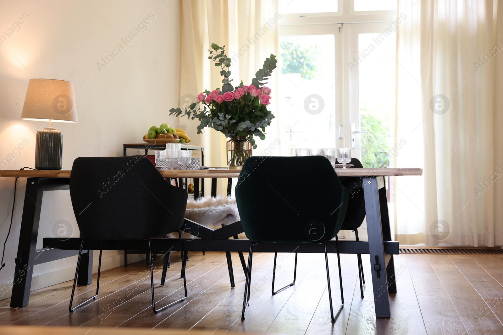 Photo of Stylish dining room with comfortable furniture, big window and bouquet of roses