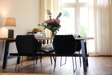 Stylish dining room with comfortable furniture, big window and bouquet of roses