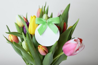 Photo of Bouquet of colorful tulips with blank card on white background, closeup
