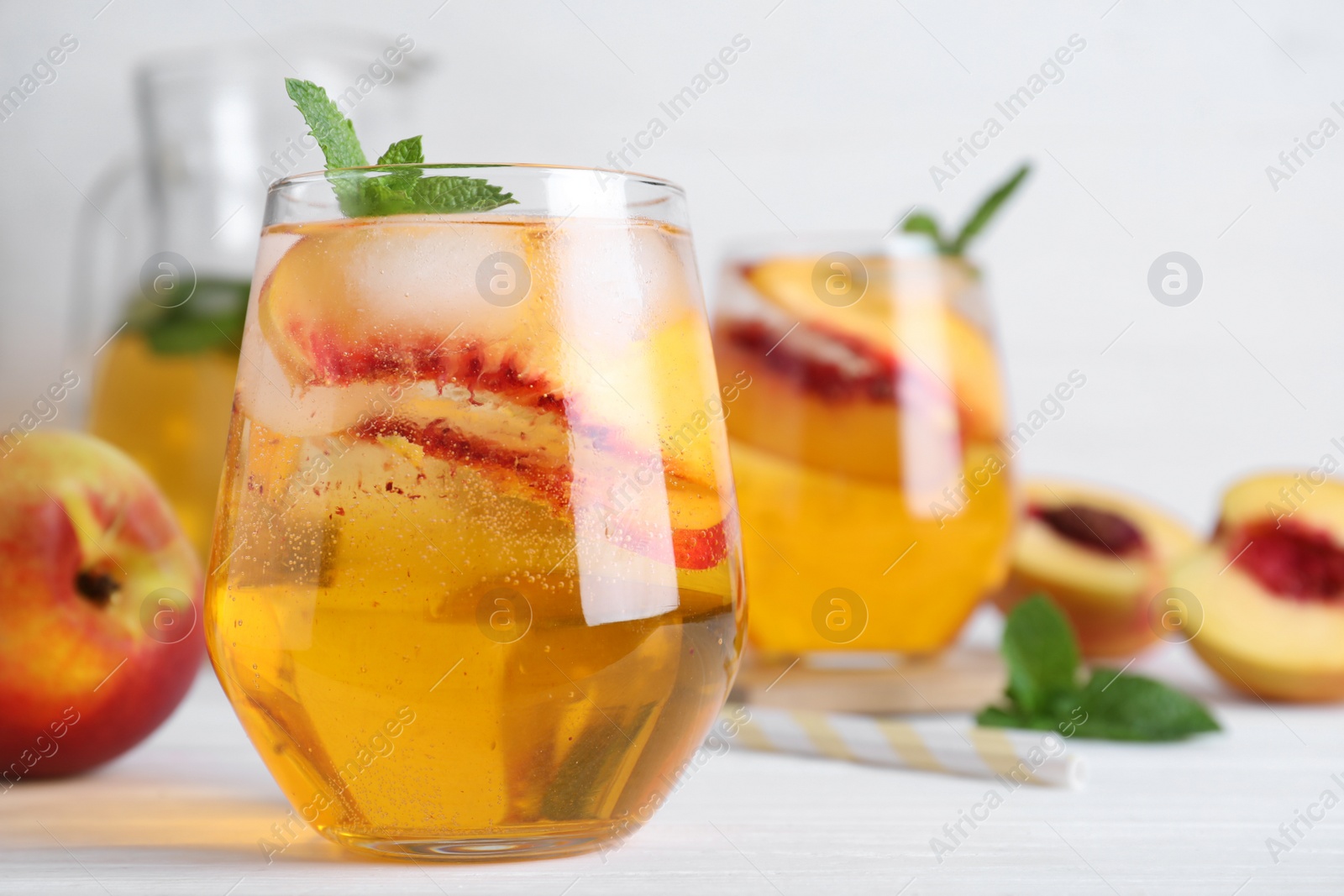 Photo of Delicious peach lemonade made with soda water on white wooden table, closeup. Space for text