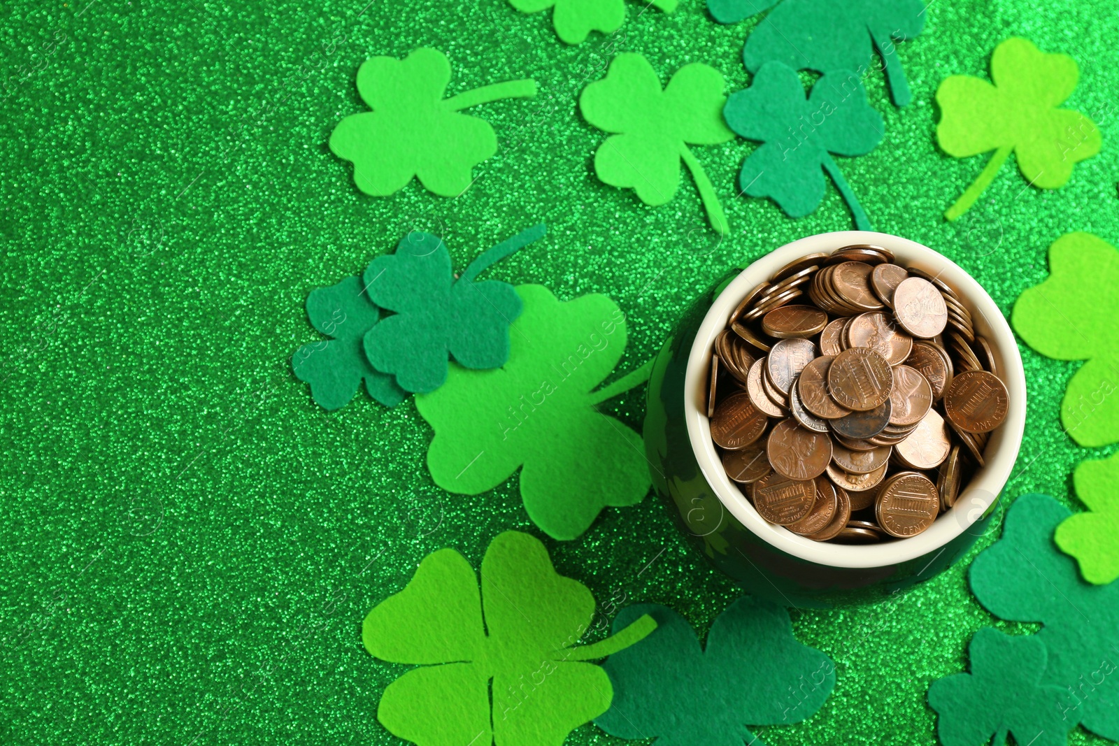 Photo of Pot of gold coins and clover leaves on green background, flat lay. St. Patrick's Day celebration