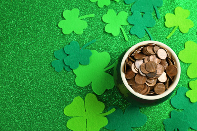 Photo of Pot of gold coins and clover leaves on green background, flat lay. St. Patrick's Day celebration