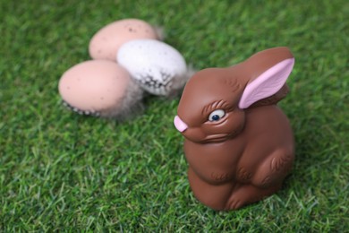 Photo of Easter celebration. Cute chocolate bunny and painted eggs on green grass