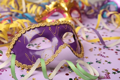 Beautiful carnival mask and party decor on violet background, closeup