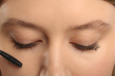 Photo of Woman applying mascara onto eyelashes, closeup view