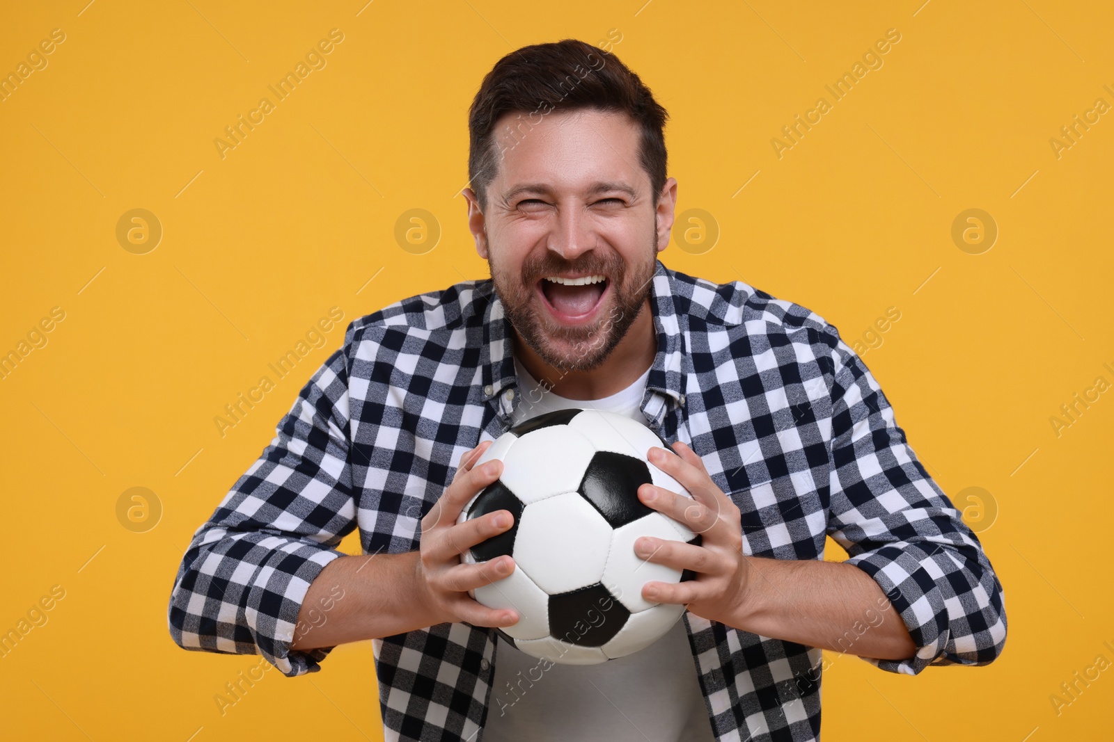 Photo of Emotional sports fan with ball celebrating on yellow background