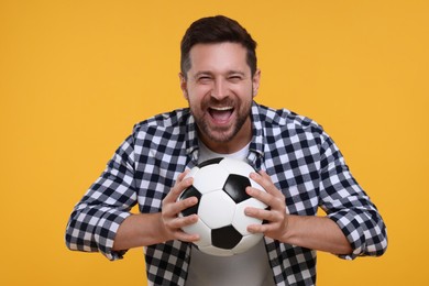 Emotional sports fan with ball celebrating on yellow background