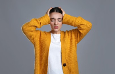 Photo of Young woman suffering from headache on grey background. Cold symptoms